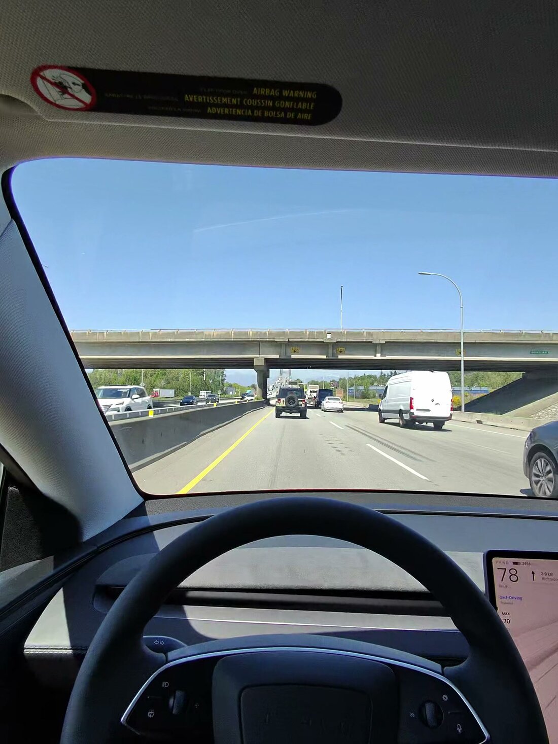 Model Y first-person POV on BC-91 in moving traffic, center display showing 78 km/h with Self-Driving engaged
